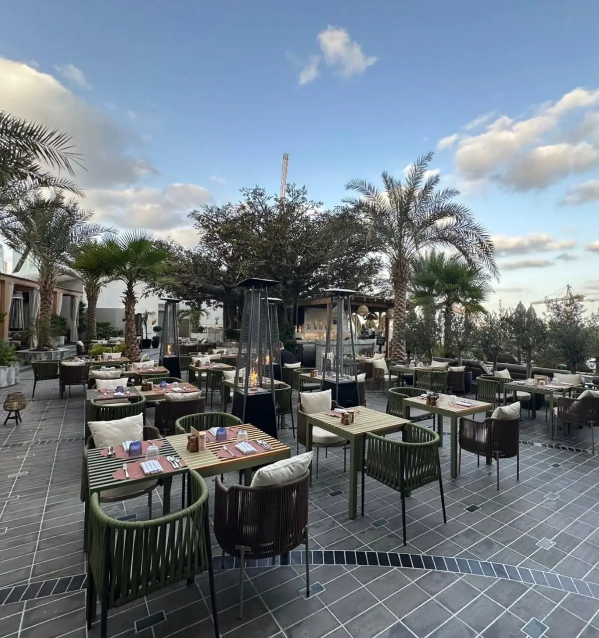Solid teak outdoor dining tables with rope-weave armchairs on a restaurant terrace in Dubai