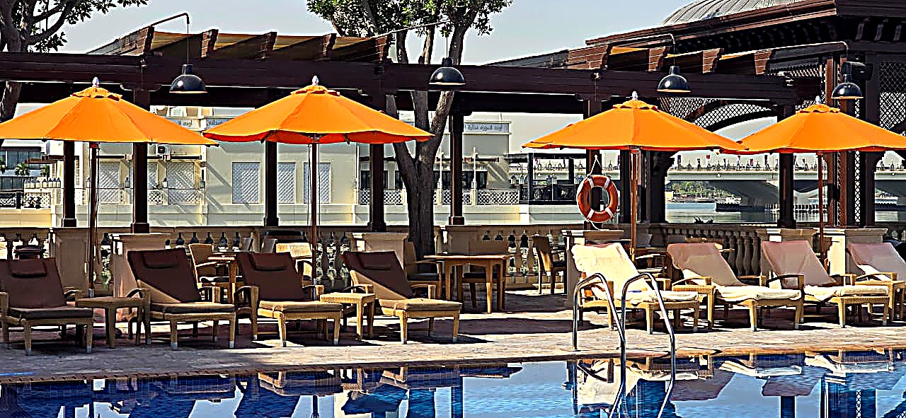 Commercial resort umbrellas and grade-A teak sun loungers on a hotel pool deck in Dubai UAE