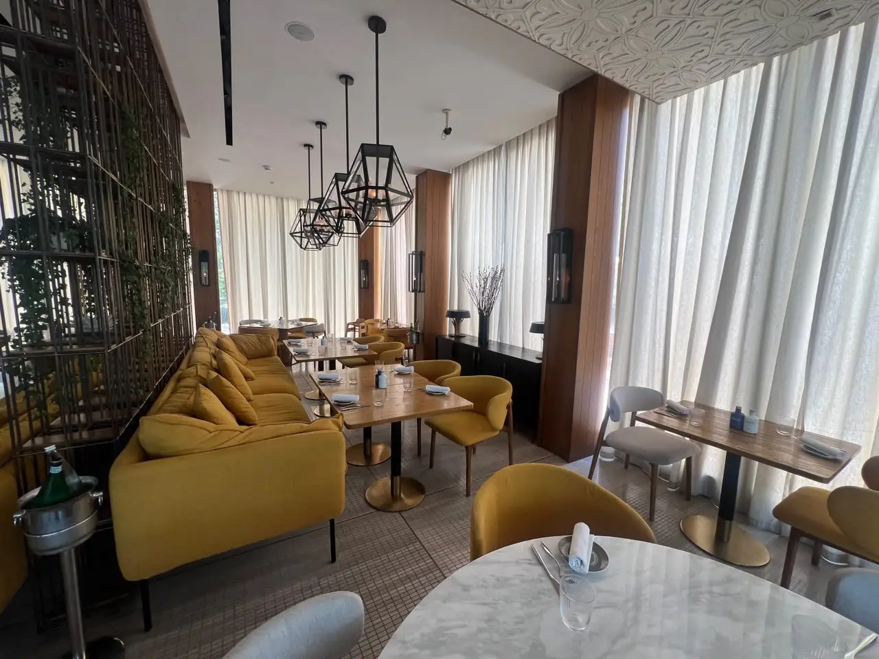 Premium restaurant interior in Dubai with upholstered sofa seating, marble and timber dining tables and upholstered armchairs supplied by Nature & Beyond International