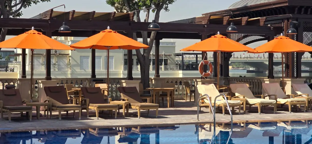 Poolside seating arrangement with orange centre-pole umbrellas, Abu Dhabi resort