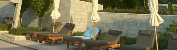 Custom teak sunloungers in guest use at a beachfront resort pool deck, Dubai